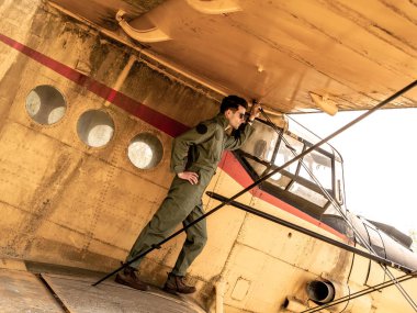 Bir uçağın kanadında duran yakışıklı genç bir pilot