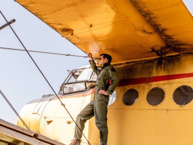 Bir uçağın kanadında duran yakışıklı genç bir pilot