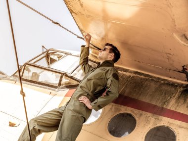 Bir uçağın kanadında duran yakışıklı genç bir pilot