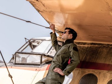 Bir uçağın kanadında duran yakışıklı genç bir pilot