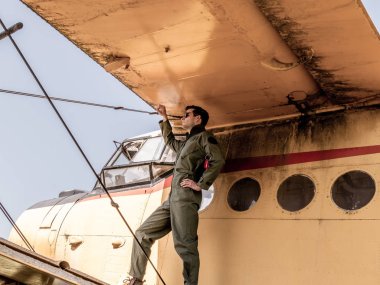 Bir uçağın kanadında duran yakışıklı genç bir pilot