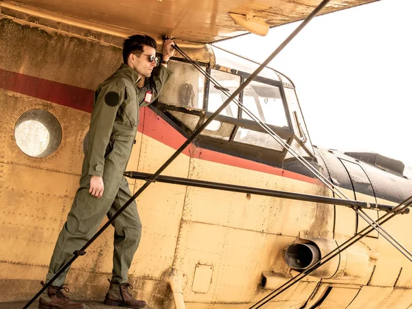 Un joven piloto guapo parado en el ala de un avión — Foto de Stock