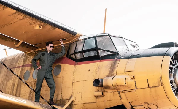 Красивый молодой пилот, стоящий на крыле самолета — стоковое фото