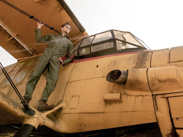 Um belo jovem piloto de pé na asa de um avião — Fotografia de Stock