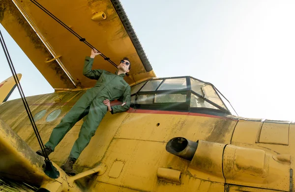 Pohledný mladý pilot stojící na křídlech letadla — Stock fotografie