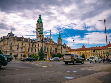 Belediye başkanının ofisinin önündeki insanlara ve arabalara bakın.