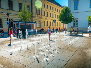 Çocuklar ve yetişkinler su kaynağıyla oynuyor.