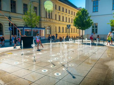 Çocuklar ve yetişkinler su kaynağıyla oynuyor.