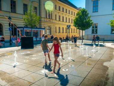 Çocuklar ve yetişkinler su kaynağıyla oynuyor.