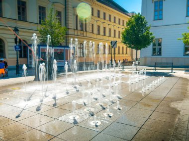 Çocuklar ve yetişkinler su kaynağıyla oynuyor.