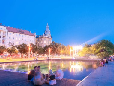 BUDAPEST, HUNGARY - 22 Ağustos 2020: İnsanlar Budapeşte, Macaristan 'da bir yaz akşamı Francis meydanında dinlenirken gün batımını izleyin.