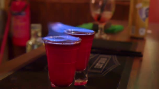 Tournage d'une flamme, déclenchant une boisson alcoolisée dans un verre dans une boîte de nuit. — Video