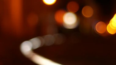 Geceleri şehirde insanlar yürürken sıcak renklerle bulanık bokeh sahnesi.