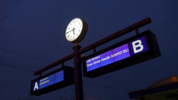 AGARD, UNGERN - ✔ RUARI 24, 2019: Vy på tågstationens informationstavla och klockan på natten i Agard, Ungern. — Stockvideo