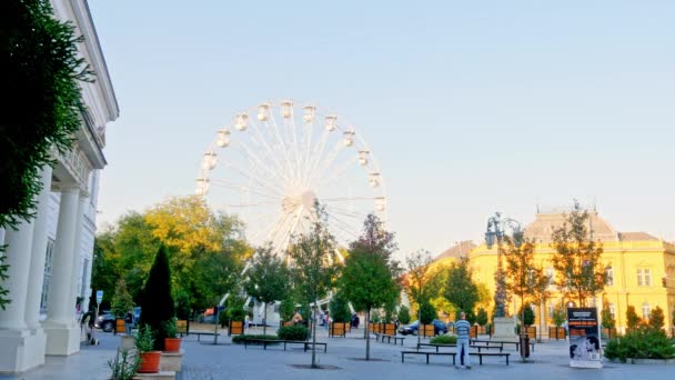 SEZKESFEHERVAR, HUNGARY - 10月26 、 2019:秋の日にハンガリーのSzekesfehervarの通りを歩く観覧車と人々を見る. — ストック動画