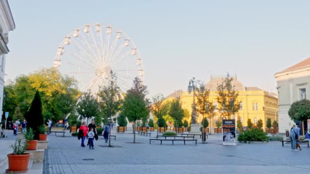 SEZKESFEHERVAR, HUNGARY - 10月26 、 2019:秋の日にハンガリーのSzekesfehervarの通りを歩く観覧車と人々を見る. — ストック動画