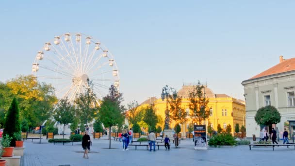 SEZKESFEHERVAR, HUNGARY - 10月26 、 2019:秋の日にハンガリーのSzekesfehervarの通りを歩く観覧車と人々を見る. — ストック動画