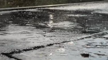 Şiddetli bir yağmur sahnesinde betonun üzerindeki yağmur damlalarının yakın görüntüsü.