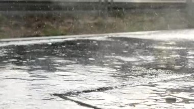 Şiddetli bir yağmur sahnesinde betonun üzerindeki yağmur damlalarının yakın görüntüsü.