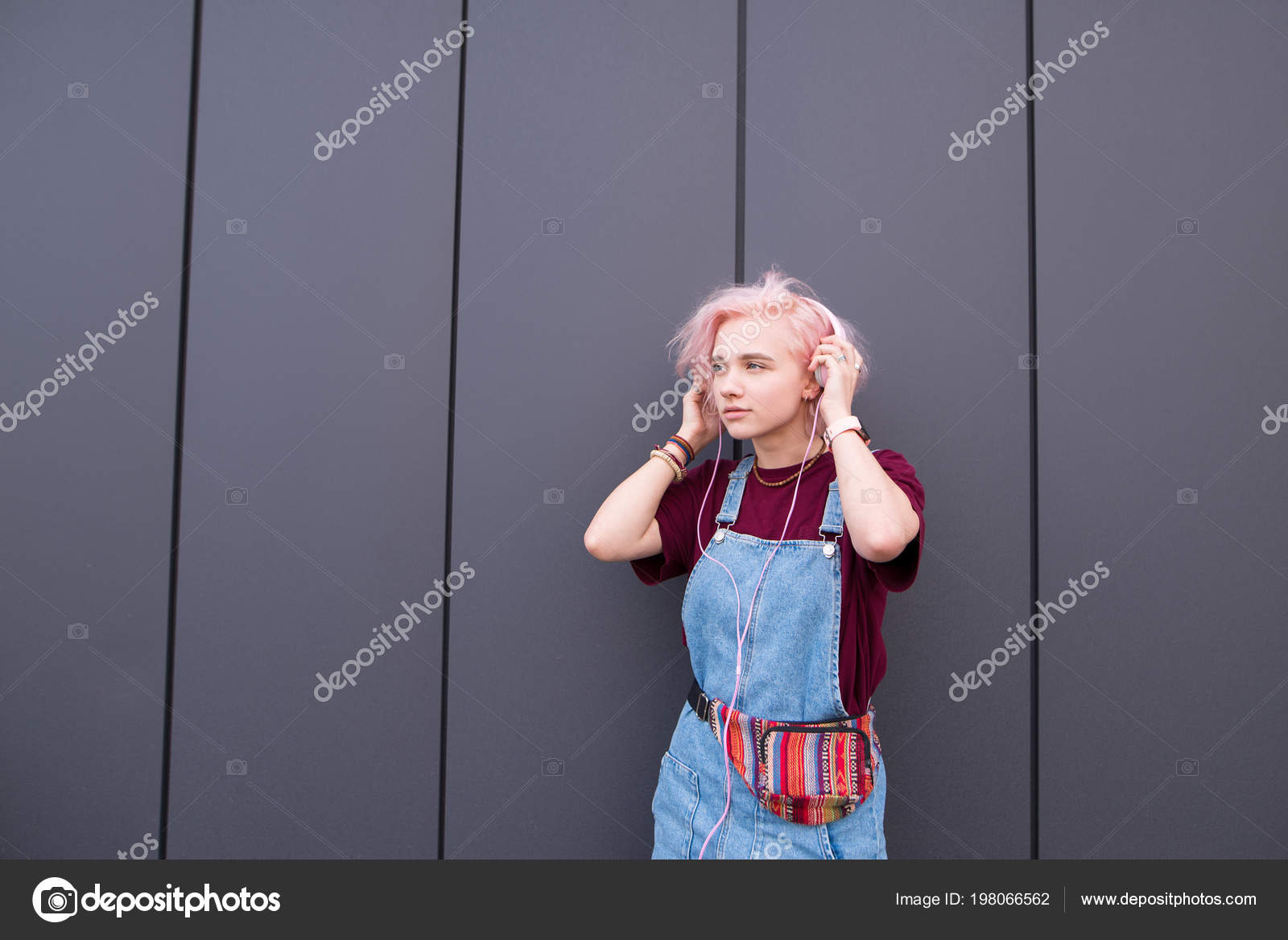 Menina ouvindo música em fones de ouvido na parede rosa. garota