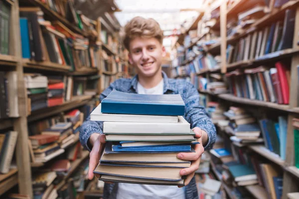 Smiling Young Man Holds Many Books His Hands Background Library — Stock Photo, Image