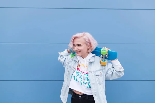 Glad Tjej Står Med Skateboard Mot Bakgrund Blå Vägg Och — Stockfoto