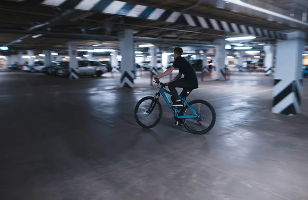 bike rider rides on an underground parking lot. A cyclist rides in an underground parking lot.