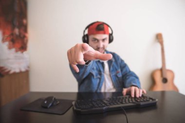 Portrait of a concentrated gamer at home playing on a computer. Emotional bearded man sitting at the computer and playing video games. Focus on hand. Video Game Concept. clipart