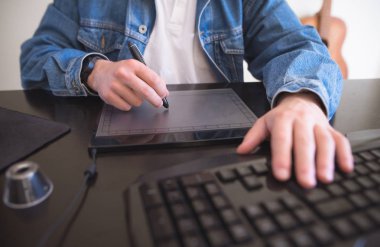 Adam bir grafik tablet evde çalışıyor. Grafik tasarımcı çevirmen evde bir bilgisayar üzerinde çalışır ve bir tablet üzerine alır.