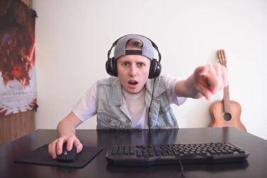 Evde bir bilgisayar üzerinde oturan ve parmağını ekranda gösterilen bir kap genç oyun kulaklıklar hayran. Bir duygusal genç bir bilgisayarda evde odada video oyunları oynamak oyun portre