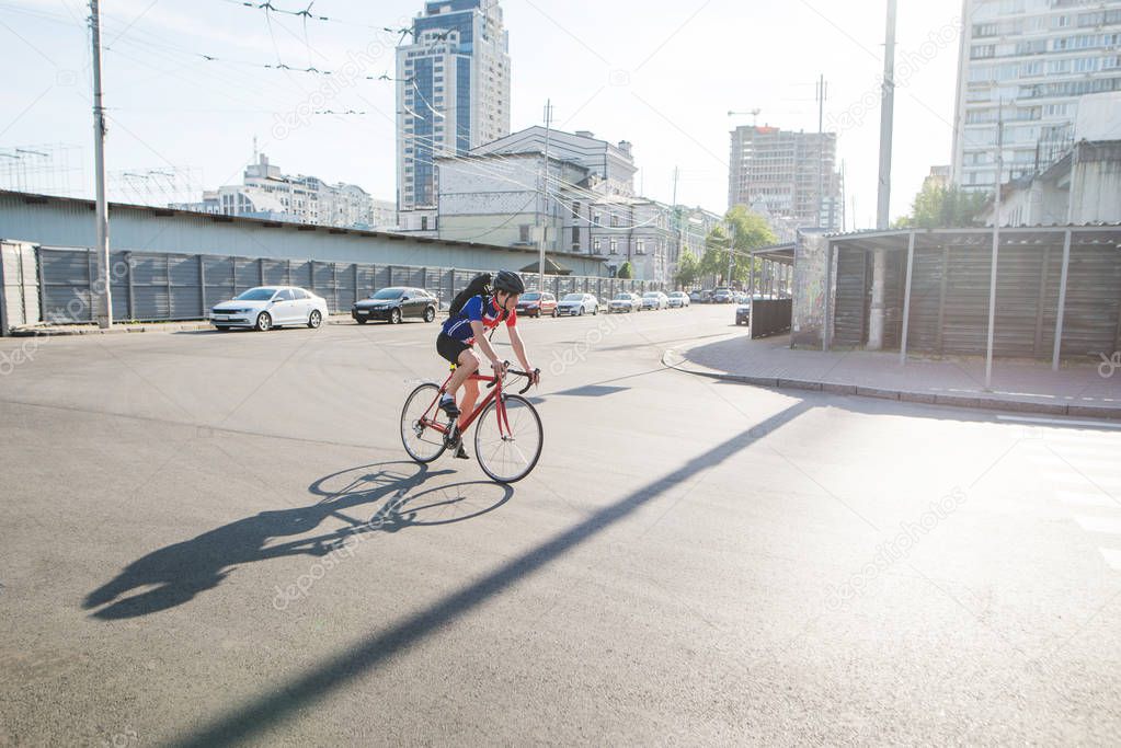 Cyclist in a helmet and athletic dress rides on a red bicycle road. A cyclist moves around the city on a city bike. An athlete riding a bike on the road. Sports concept