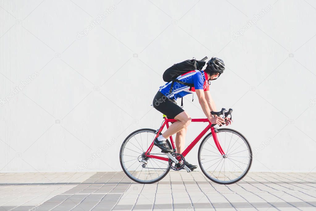 Portrait of a cyclist athlete on the move against the background of a white wall. Man cycling cyclist on a white background. side view . Sports concept. Copyspace