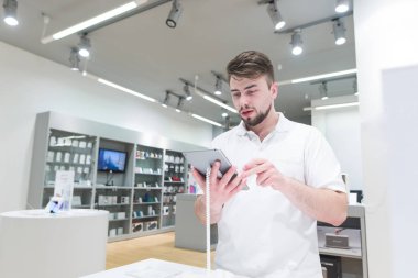 Modern bir ışık teknoloji olan bir tablet seçen alıcı portresi saklayın. Gadget'ı elektronik mağazasında seçin. Adam deposundaki bir tablet satın alır..