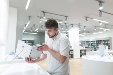 Yakışıklı bir ışık teknik mağaza içinde a defter bakar. Bir alıcı bir defter bir modern elektronik mağazasında seçer. Bir gadget satın.