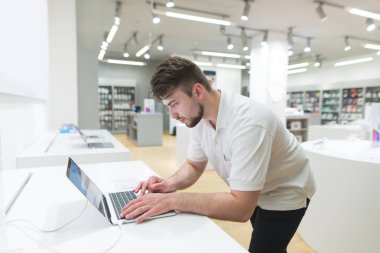 Yakışıklı bir dizüstü şık iç mekanlara modern teknoloji deposuyla kullanır. Alıcı belgili tanımlık defter elektronik mağazasında seçer..