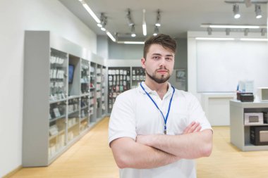 Adam teknik danışman portresi. Kameranın hafif elektronik mağazasından arka plan üzerinde Danışmanı pozlar.