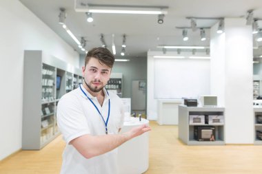 Yakışıklı adam danışmanı olarak beyaz bir T-shirt elektronik mağazaya davet ediyor. Bir konser bir modern teknoloji Mağazası portresi. İş danışmanı elektronik mağaza
