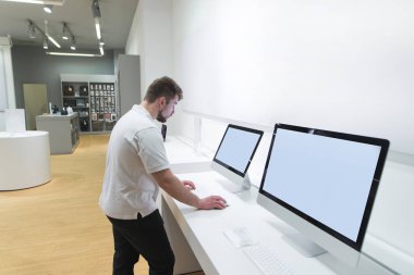 Alıcı bir monoblok bilgisayar bir modern teknoloji deposunu kullanır. Bir sakallı bir adam bir elektronik mağazasından bir bilgisayar seçer. Modern bir bilgisayar satın alma.