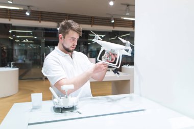 Yakışıklı adam modern ışık dron deposunda. Seçme ve bir quadcopter elektronik mağazasında satın alma.