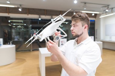 yakışıklı adam modern elektronik mağazasından dron bakar. Bir ışık teknik deposunda bir quadcopter seçin