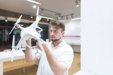 Yakışıklı adam modern ışık dron deposunda. Seçme ve bir quadcopter elektronik mağazasında satın alma. Bir ışık teknik deposunda bir quadcopter seçin