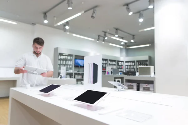 Showcase with tablets in the technology store. Buyer chooses a tablet in the electronics store. Focus on the showcase and the tablets.