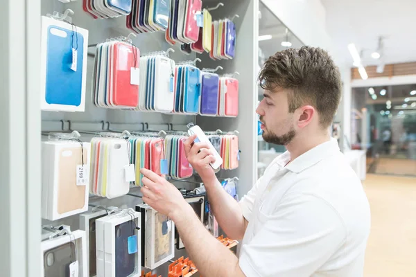 Adam akıllı telefonlar için aksesuarları depolamak için durumlarda seçer. Bir smartphone bir teknoloji Mağazası için aksesuarlar satın alma. Alıcı bir telefon dava seçer