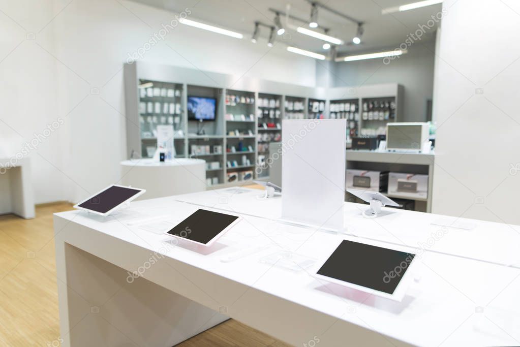 Showcase with tablets in the light modern tech store. Tablets on a showcase in a light electronics store.