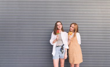 Kendi el ve grunge şeker ile gri bir arka plan üzerinde ışık kılığına girmiş iki pozitif kız arkadaşım vardır.