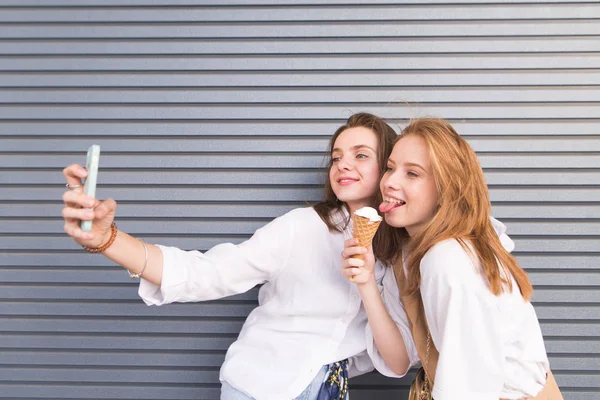 Дві Щасливі Привабливі Подружки Роблять Сефі Смартфоні Тлі Сірої Стіни — стокове фото