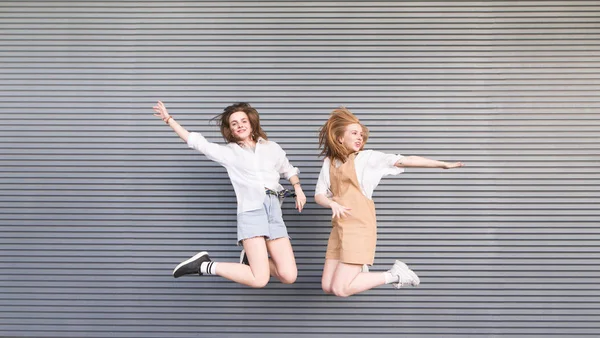 Two Stylish Happy Girls Jump Together Gray Background Portrait Smiling — Stock Photo, Image
