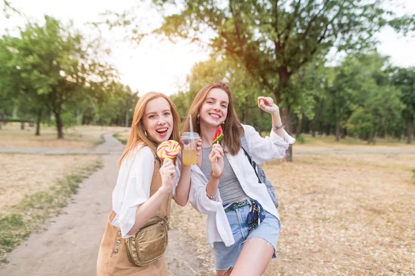 Boldog Mosolygó Lányok Cukorkát Limonádé Kezükben Pózol Kamera Háttérben Park — Stock Fotó