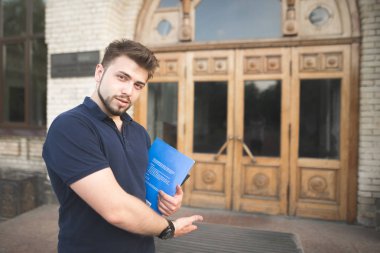 Kapı ve davet eliyle onun el tezgahı kitap ve sakalı olan adam. Bir öğrenci üniversite kapıda duruyor ve kameraya benziyor