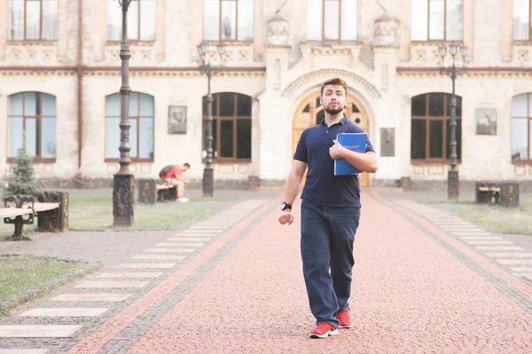 Mutlu erkek öğrenci kitapları ile kampüs arka üzerinde elinde gidiyor. Sakal ve kitaplar onun elinde sokak üniversite arka plan üzerinde yürüme ile tam yetiştirilen, komik bir adam portresi